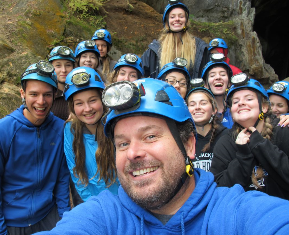 a teacher and group of students wearing helmets with lights on them